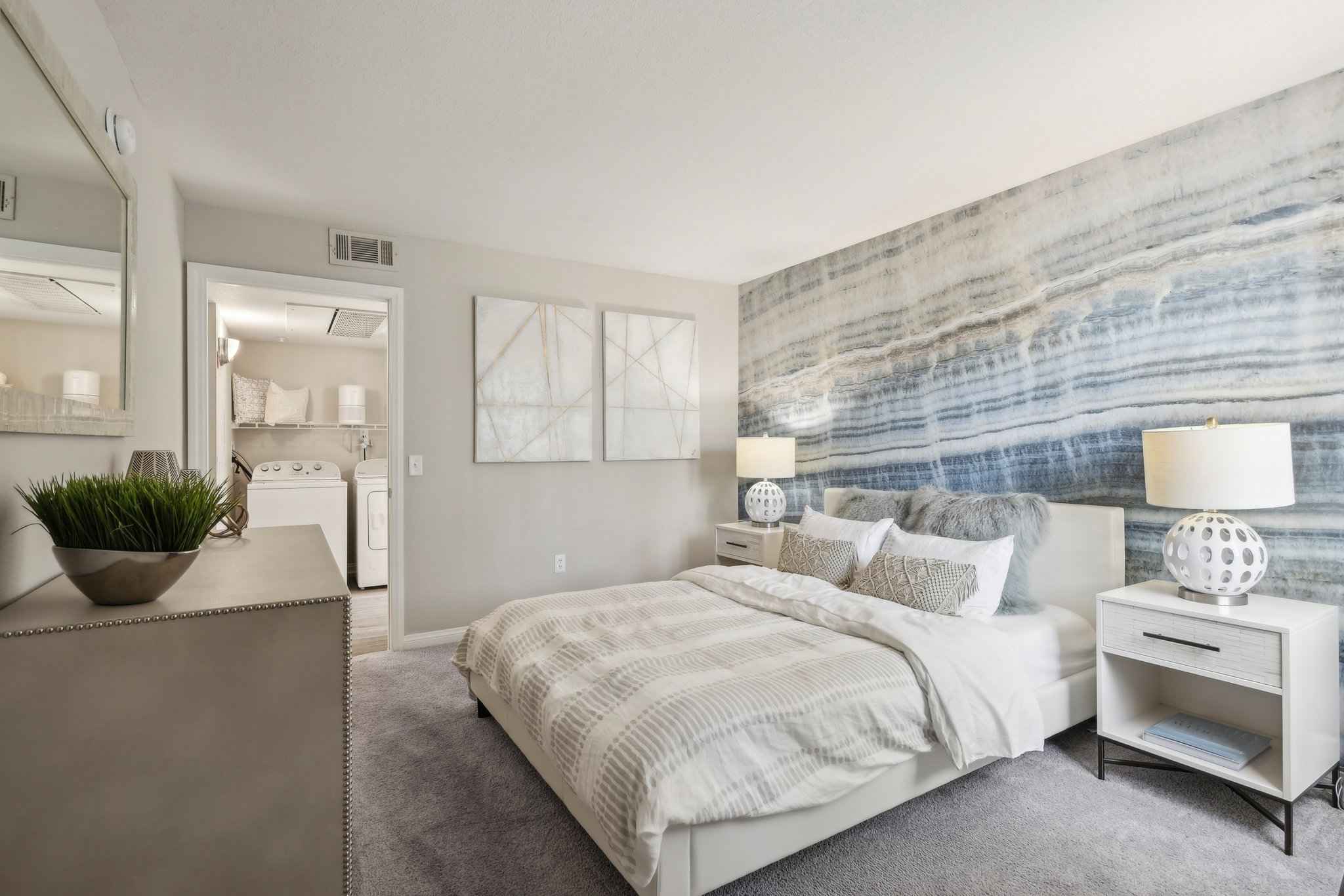 bedroom with bed decorative wall showing room with washer dryer at Millennium East