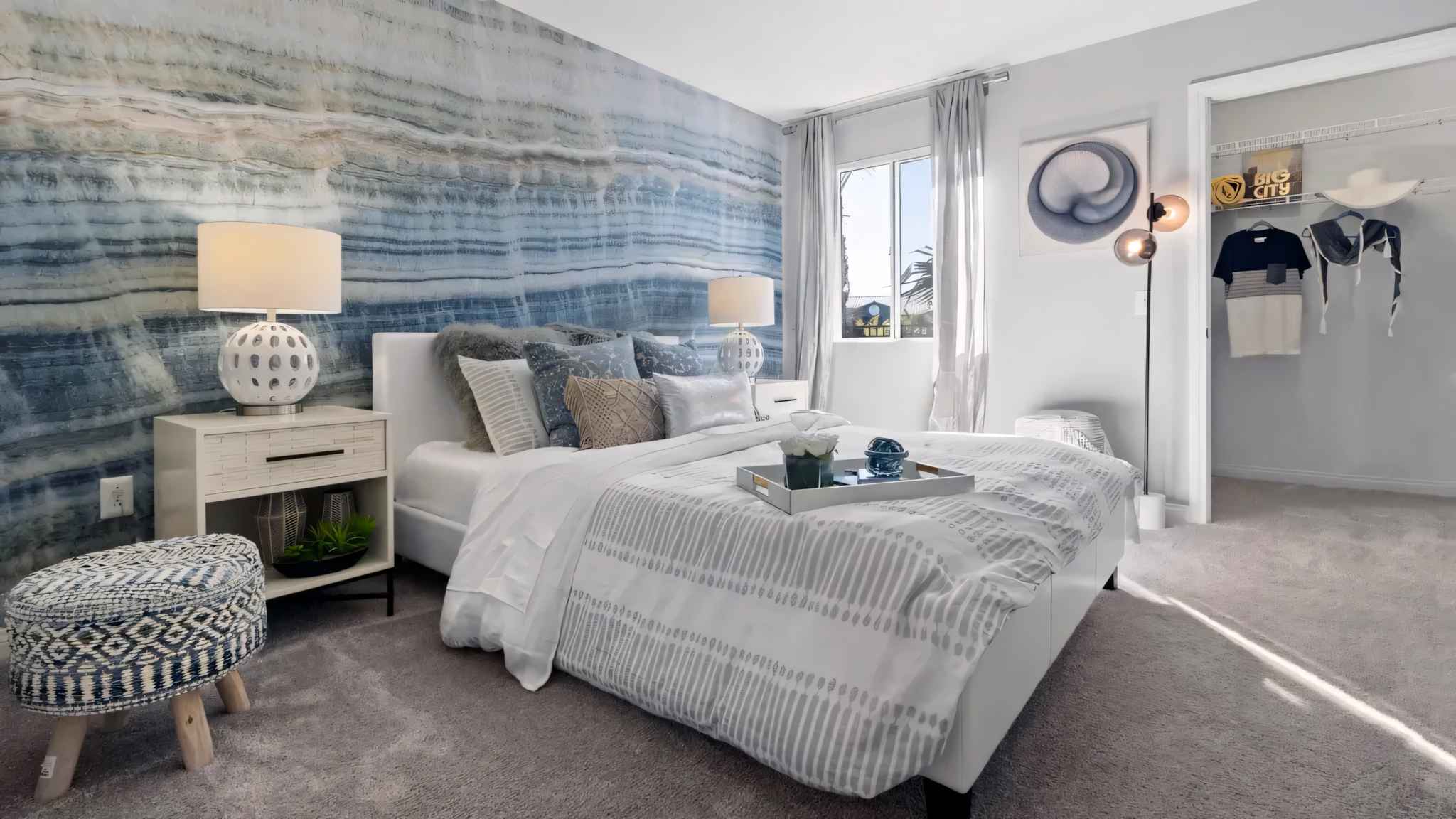 bedroom with bed with decorative tray and window view of showing outside and walk in closet at Millennium East