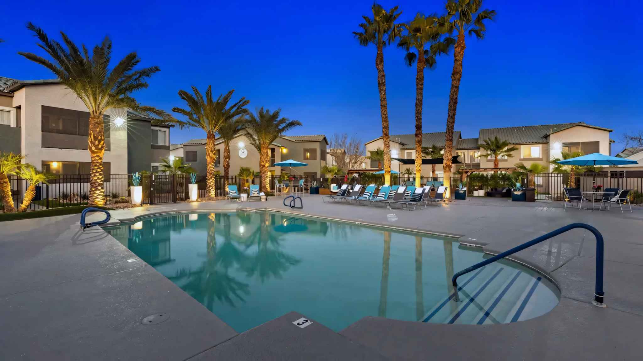 brightly lit community pool at night with lounge chairs at Millennium East
