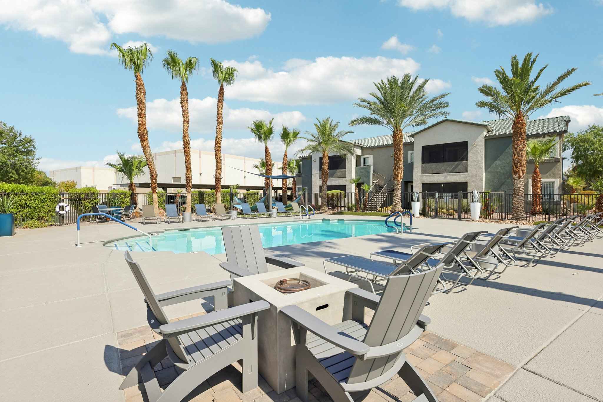 community pool lounge area showing pool chairs and entrance to building and palm trees in the background at Millennium East