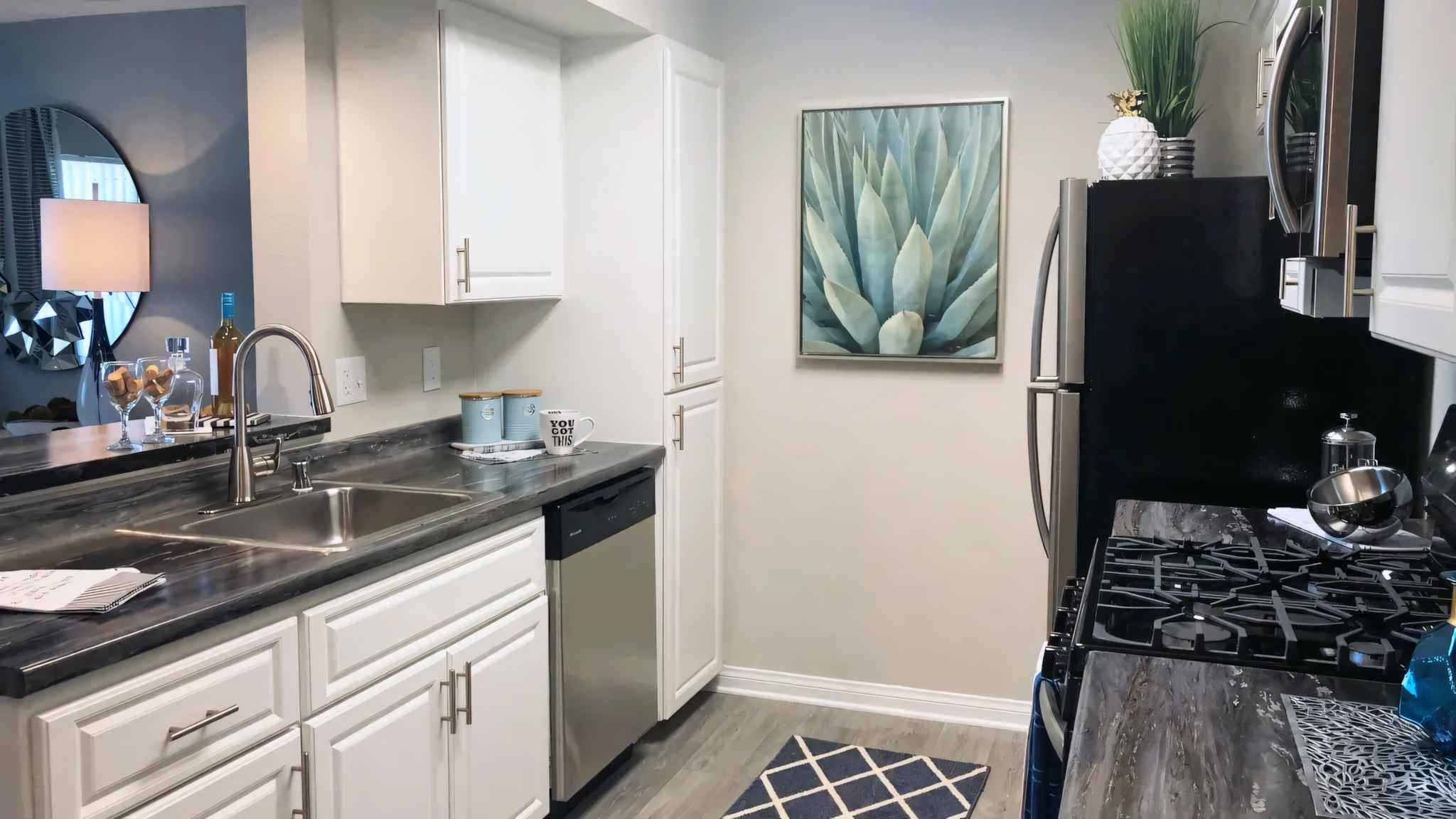 kitchen closer view of kitchen stainless steel sink and counter space with storage cabinets and oven and refrigerator at Millennium East